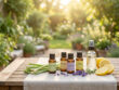 Bouteilles d'huiles essentielles (citronnelle, lavande, eucalyptus citronné), ingrédients et spray sur table de jardin ensoleillée.